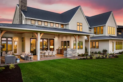 Exterior of a large farmhouse-style home in DFW showcasing multiple replacement windows and sliding glass doors at sunset.